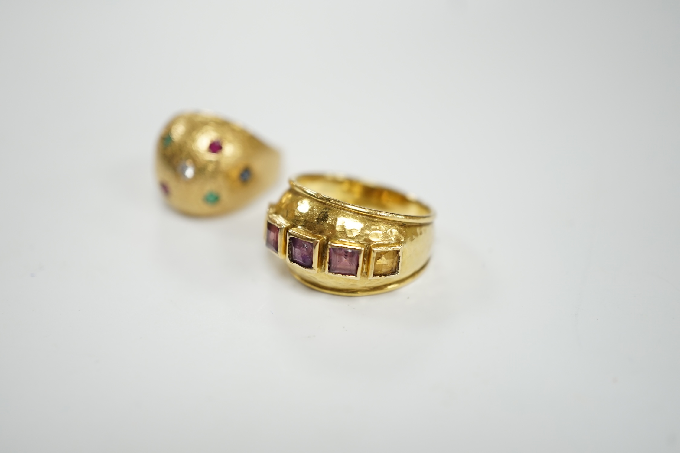 A textured yellow metal, emerald, ruby and diamond set domed ring, size K, together with a stylish yellow metal and graduated square cut amethyst set five stone ring, size M, gross weight 13.1 grams.